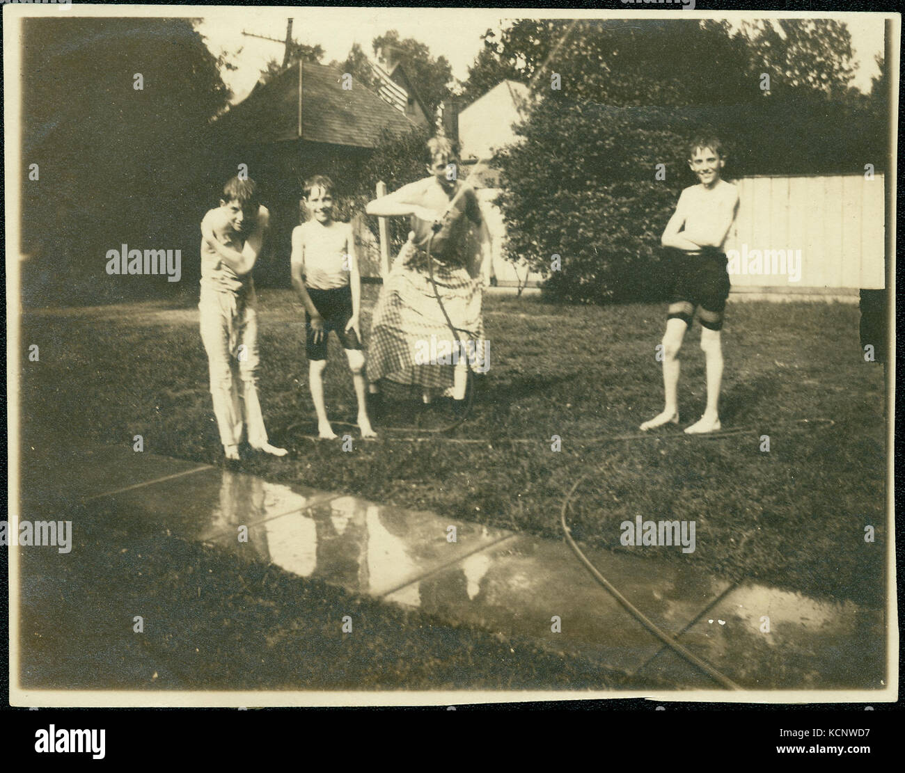 Quattro ragazzi associati con la famiglia di Lione a giocare all'aperto e con un tubo flessibile di acqua Foto Stock