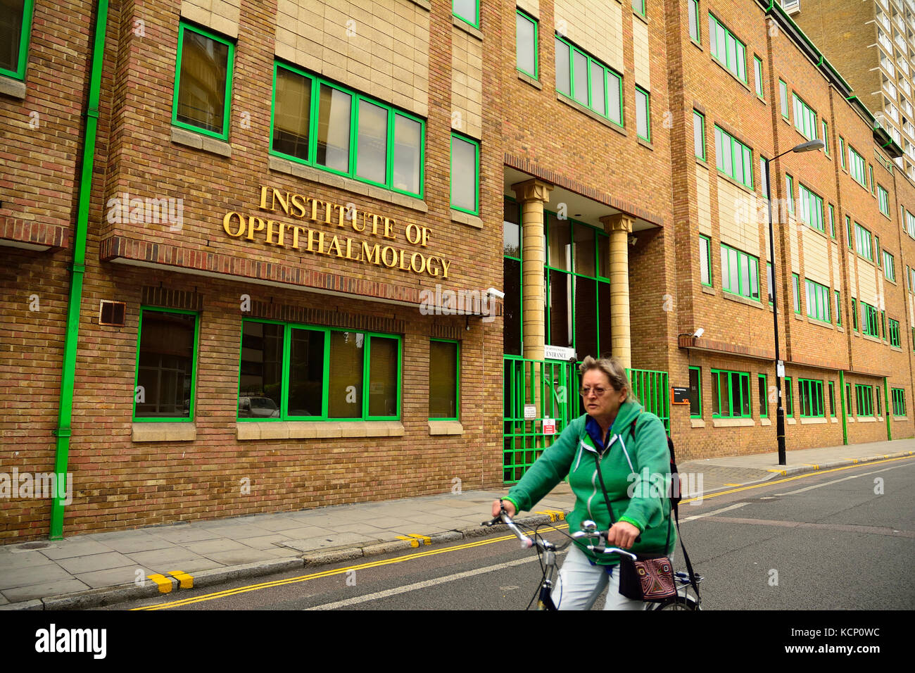 Istituto di Oftalmologia con la donna ciclista in Londra, Regno Unito Foto Stock