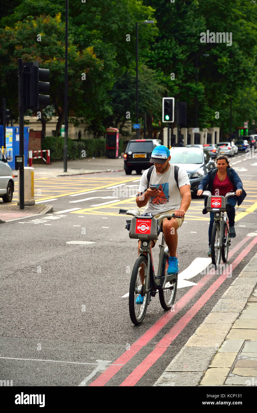 Ciclista utilizza lo smartphone mentre in sella a Londra, Regno Unito Foto Stock