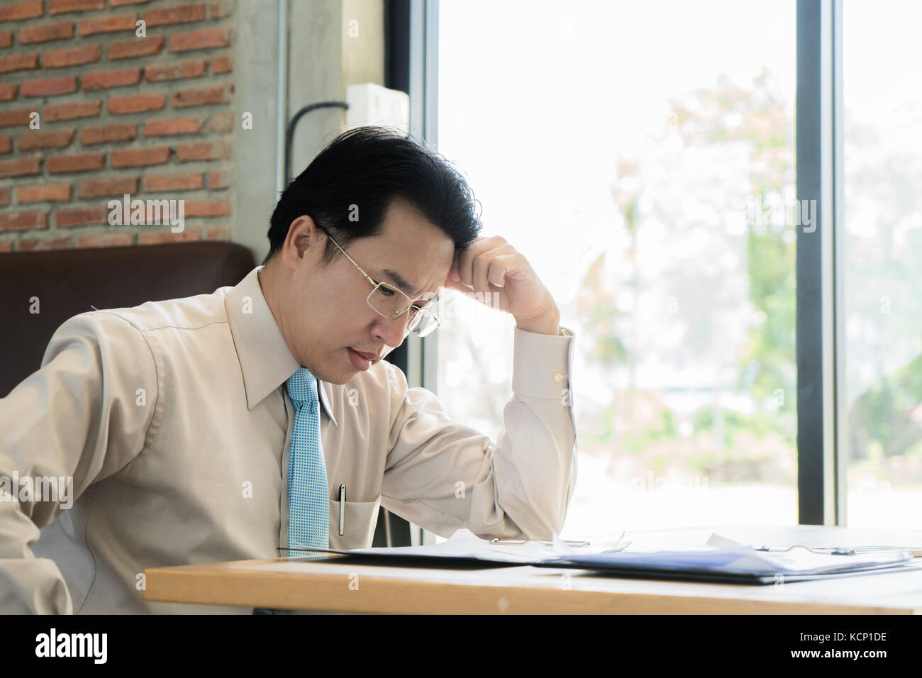 Imprenditore asiatico seduto e pensando al cafe, cercando frustrato e depresso. Foto Stock