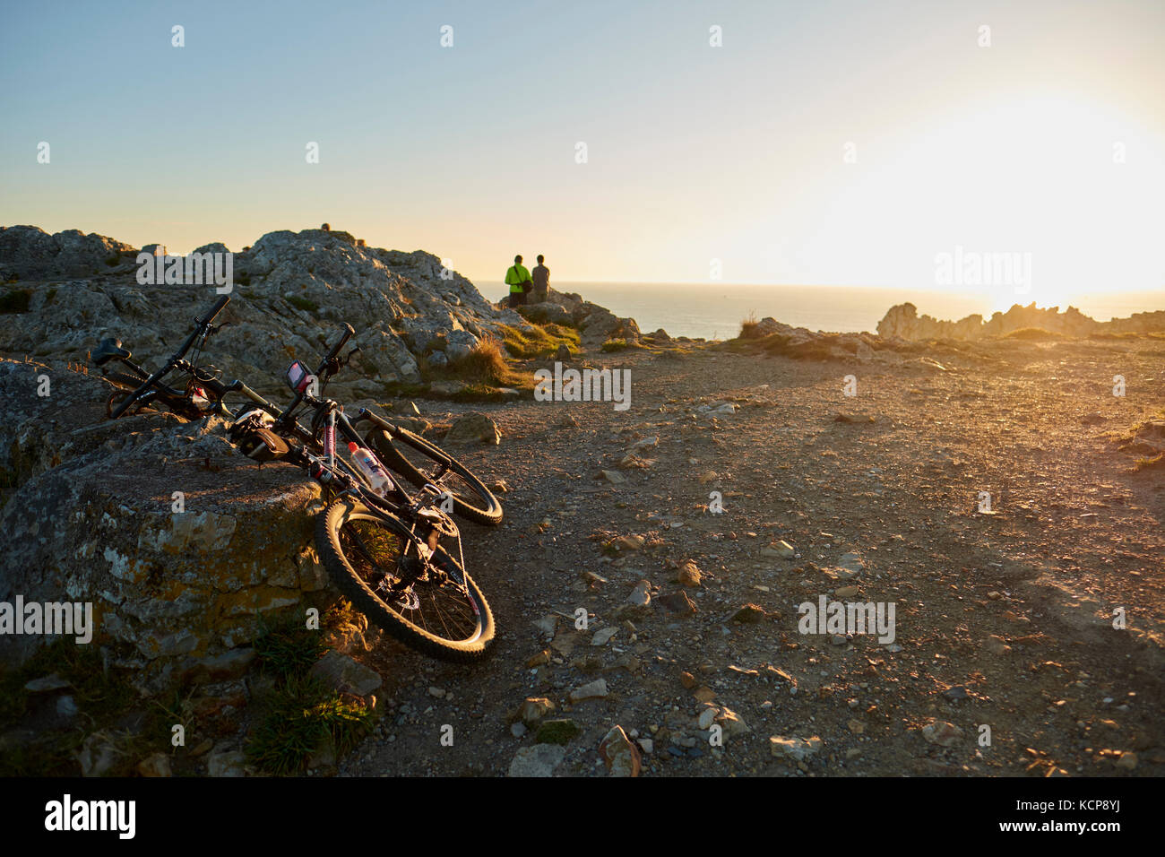 I ciclisti a guardare il tramonto sulla costa frastagliata di Pen Hir Finistere Bretagna Francia Foto Stock