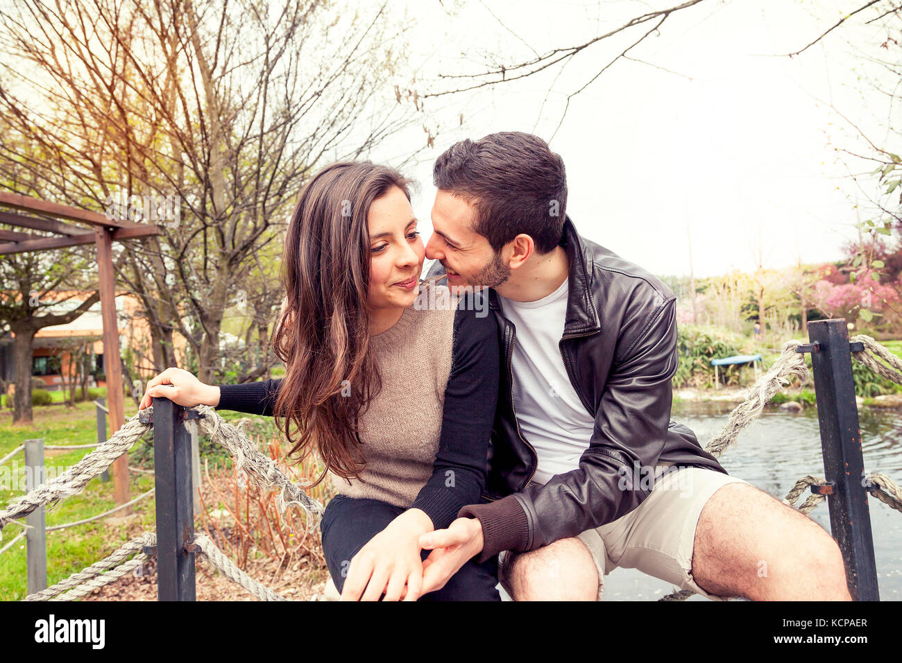 Bella coppia di fidanzati abbraccia e bacia su un ponte di legno nel parco  Foto stock - Alamy