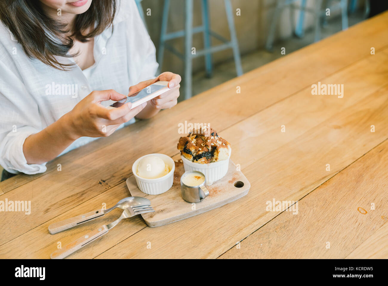 Ragazza asiatica prendendo foto di toast al cioccolato torta, gelato, latte e presso la caffetteria. dessert o cibo hobby fotografia presa dal concetto dello smartphone Foto Stock