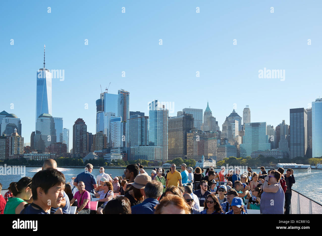 Le persone e i turisti a scattare foto e guardando a New York skyline della città dal traghetto in una giornata di sole Foto Stock