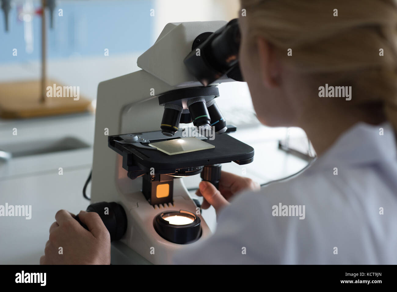 Studente universitario facendo esperimento su microscopio in laboratorio presso il college Foto Stock