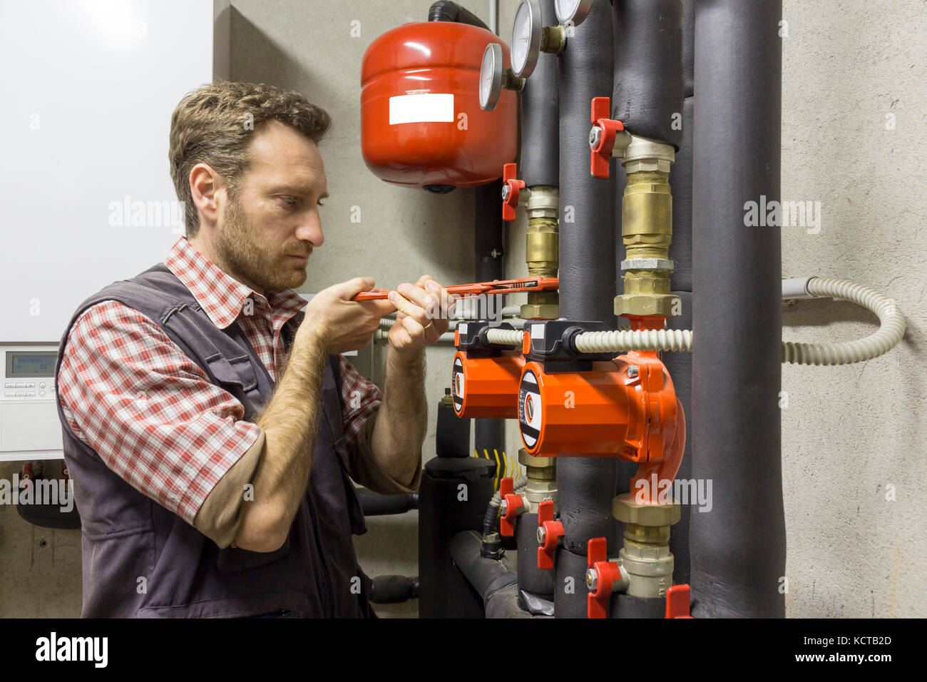 Plumber al lavoro di installare una pompa di circolazione Foto Stock