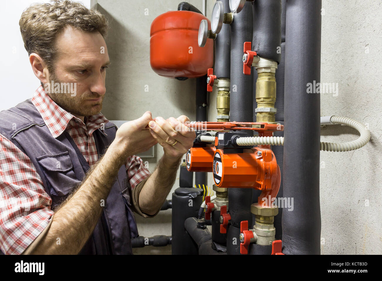 Plumber al lavoro di installare una pompa di circolazione Foto Stock