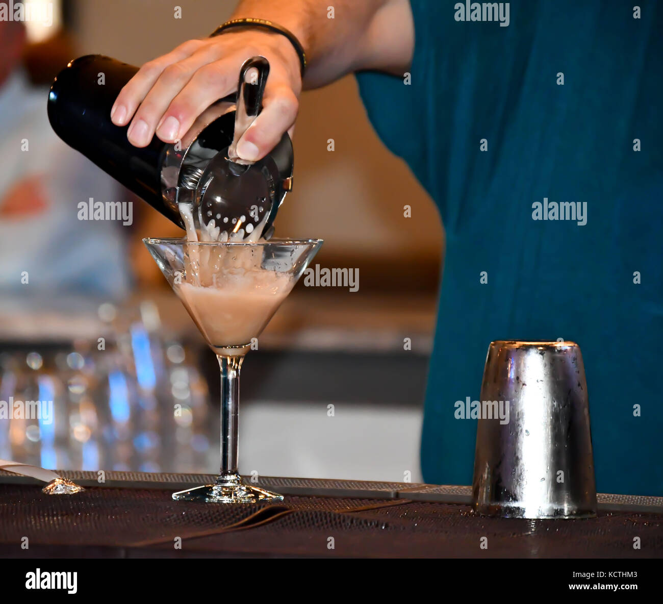 Il barista in un bar informale di colata e la miscelazione di bevande e liquori Foto Stock