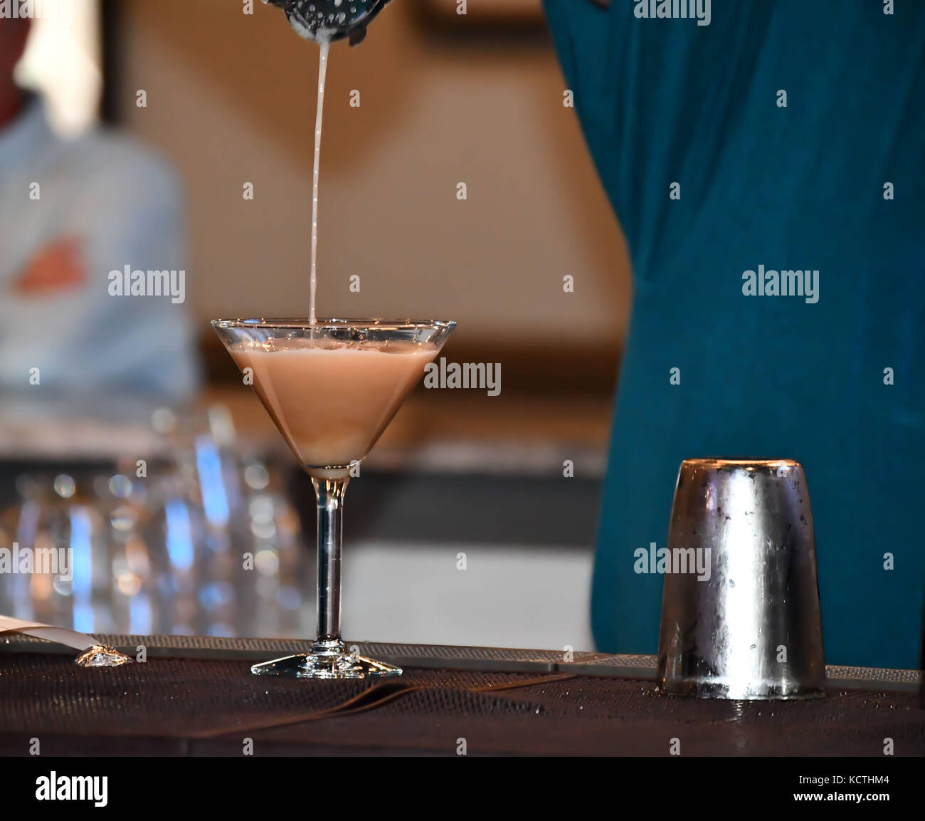 Il barista in un bar informale di colata e la miscelazione di bevande e liquori Foto Stock