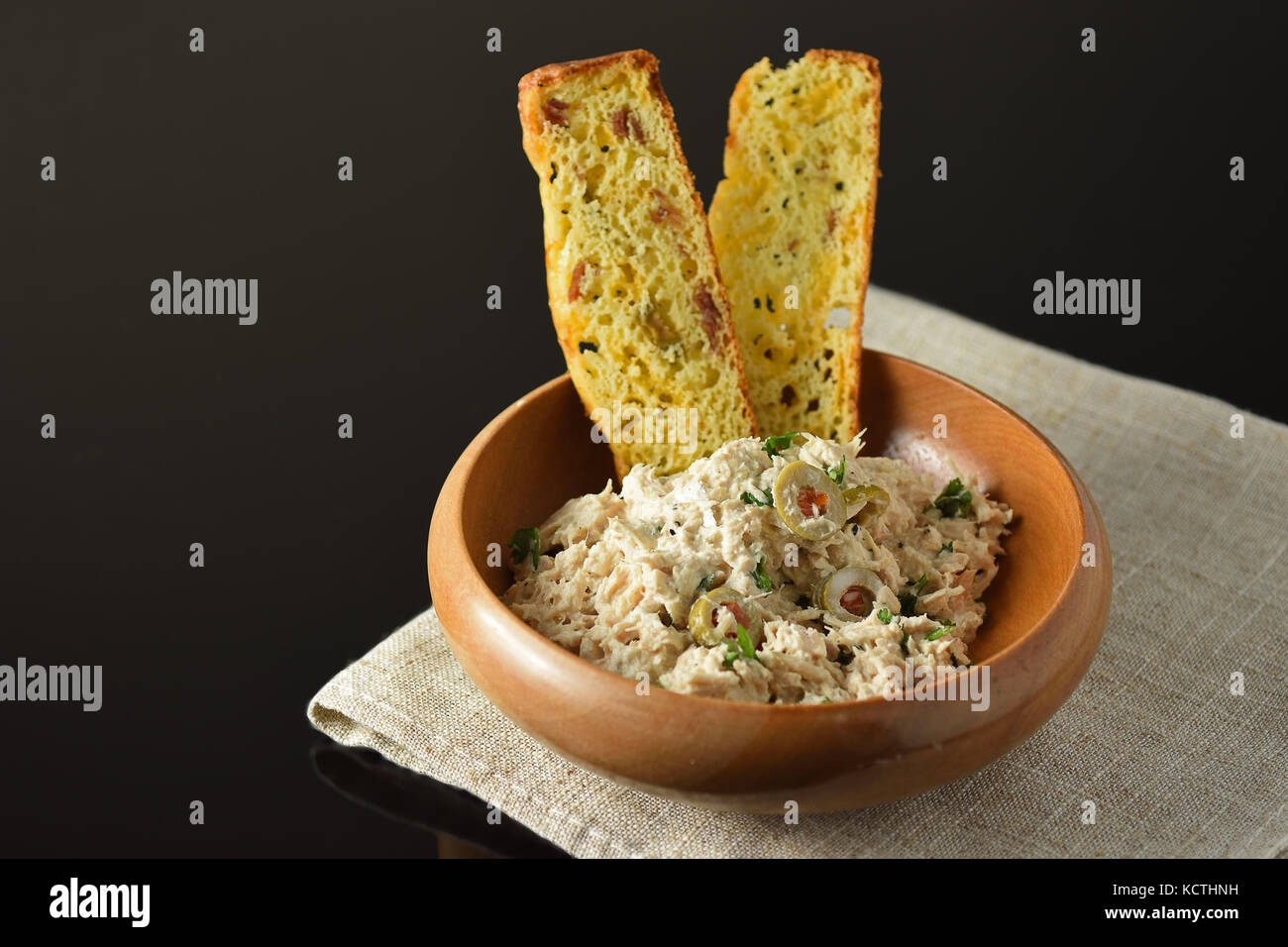 Ciotola di legno con insalata di tonno su una superficie nera Foto Stock