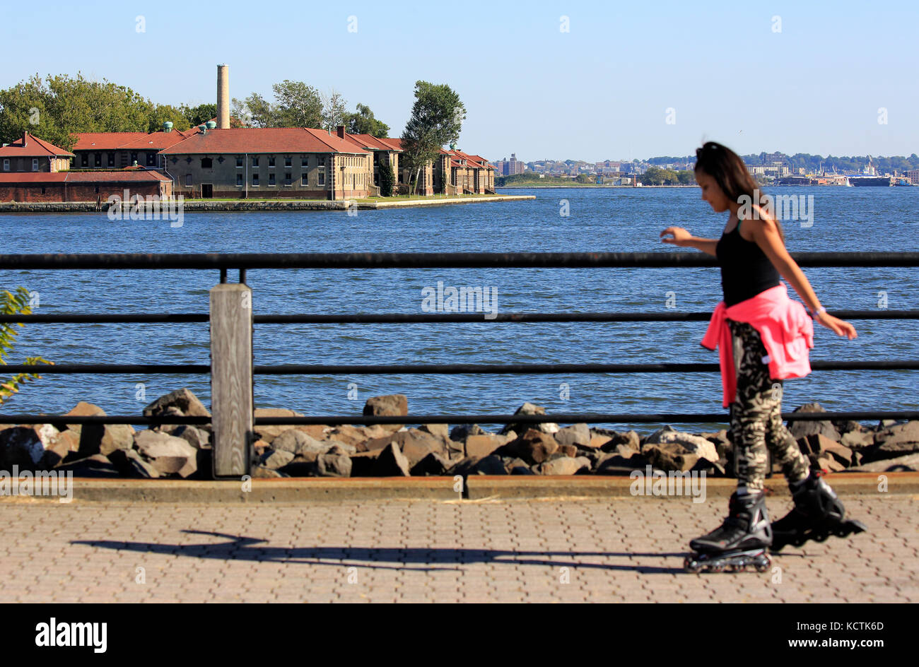 Una ragazza che rollerblading nel Liberty state Park con lo storico Ellis Island Immigrant Hospital in background.Jersey City.New Jersey.USA Foto Stock