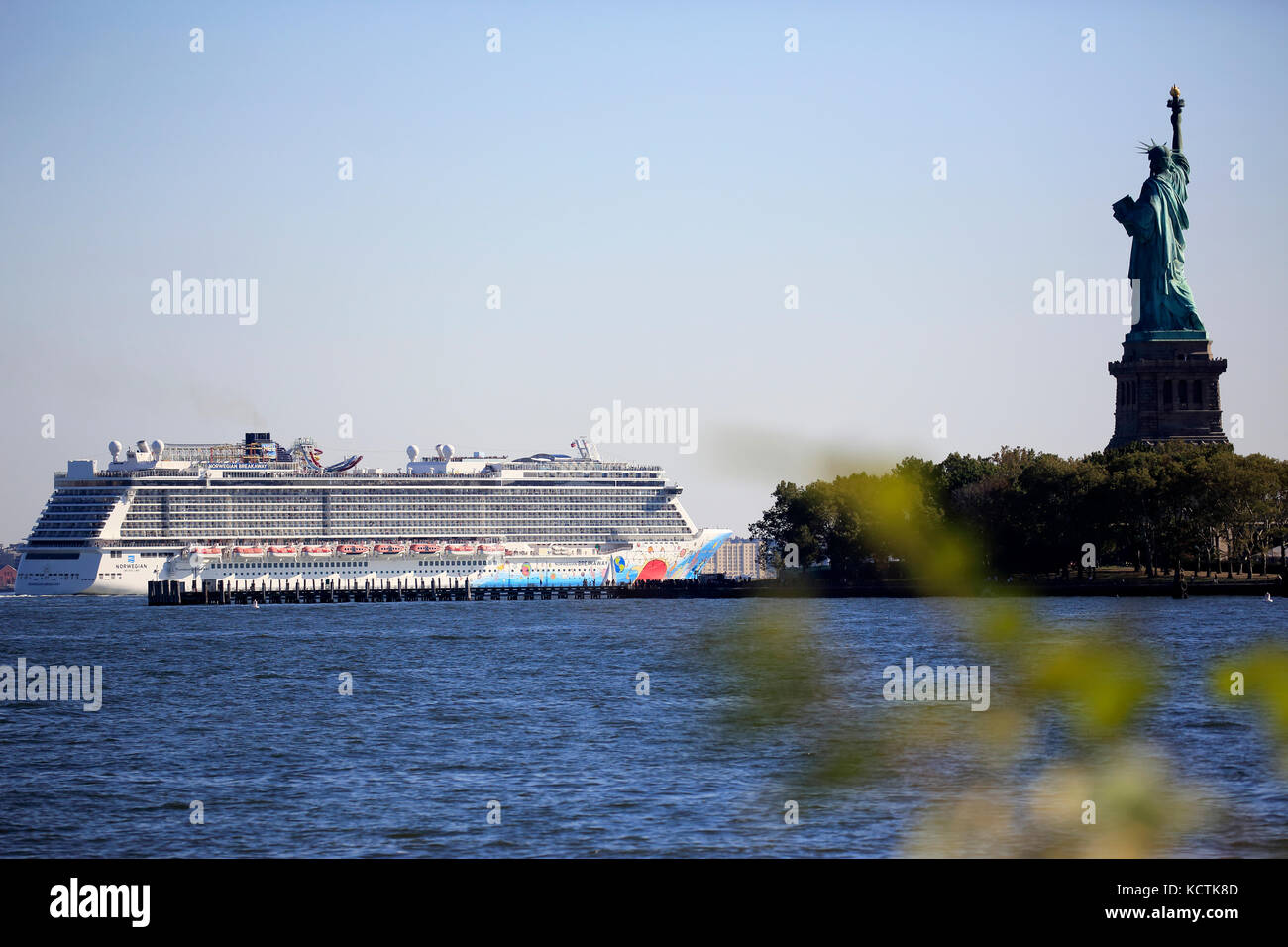 Norwegian Breakaway nave da crociera passando Liberty Island con la Statua della Libertà accanto nel porto di New York. New York City.New Jersey.USA Foto Stock