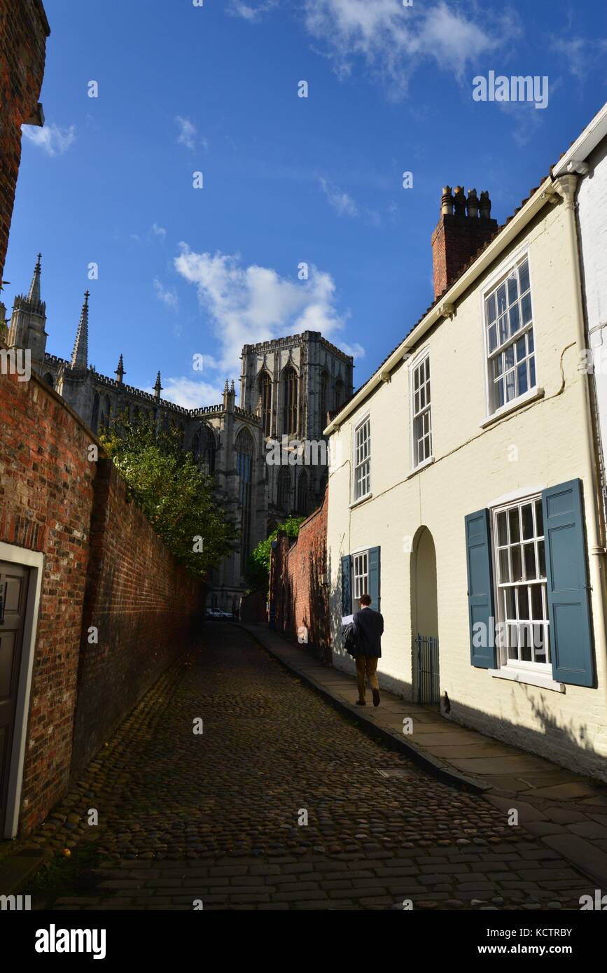 Strada di ciottoli, chiesa in background, York, North Yorkshire Foto Stock