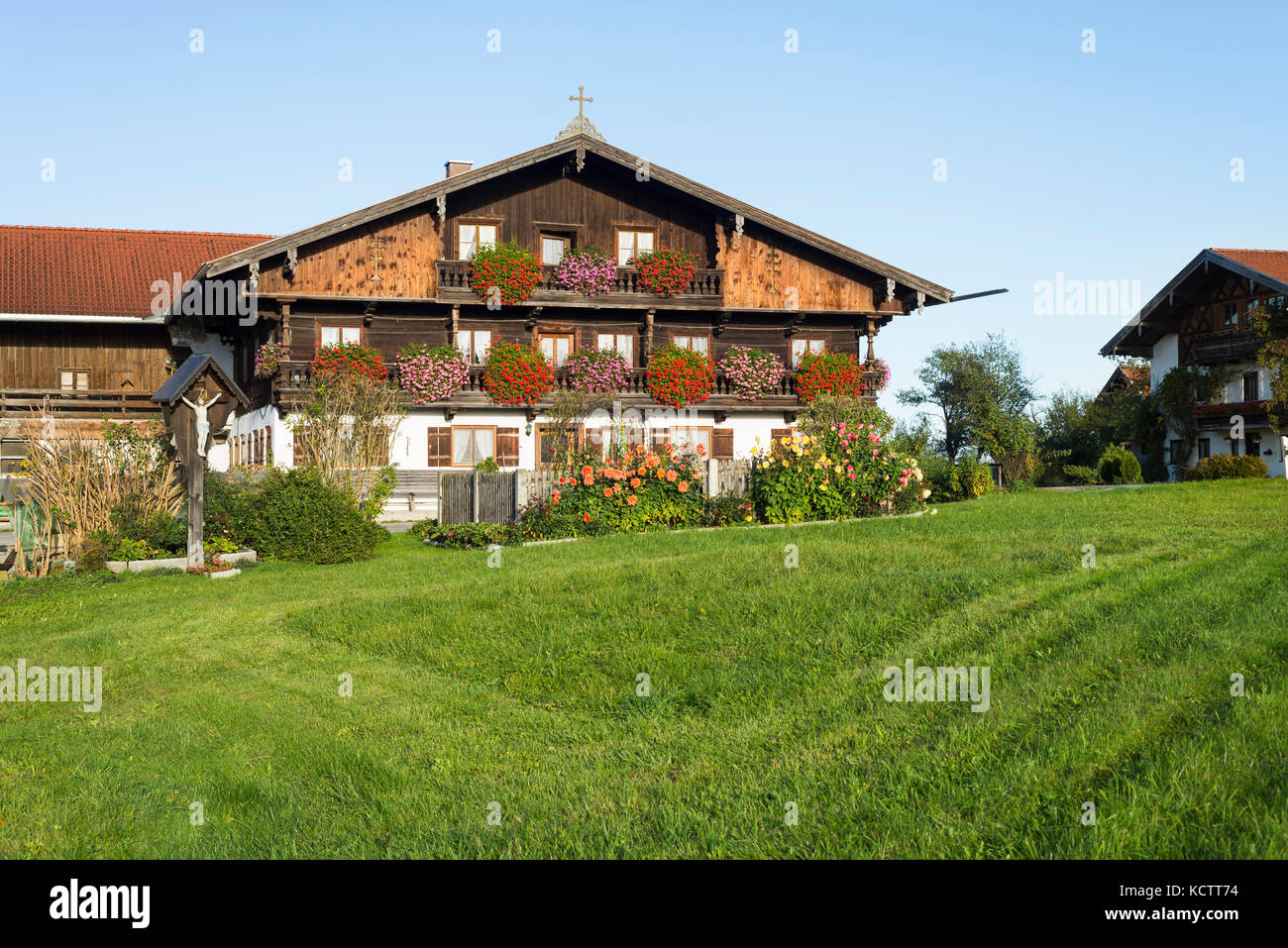 Case coloniche con facciata in legno nel tradizionale stile bavarese in Baviera con fiori che sbocciano nel sole del mattino, irschenberg, Baviera, Germania Foto Stock