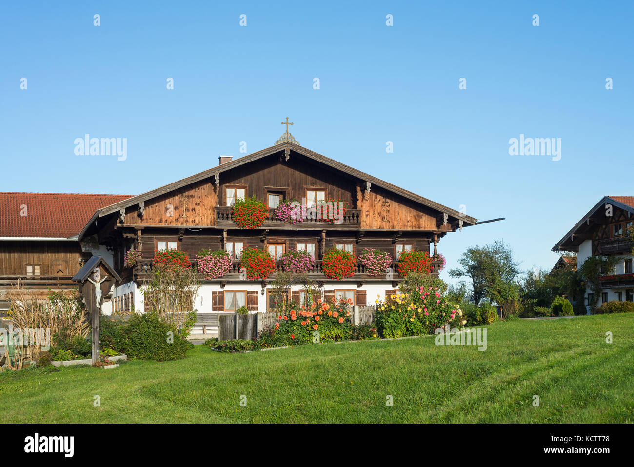 Case coloniche con facciata in legno nel tradizionale stile bavarese in Baviera con fiori che sbocciano nel sole del mattino, irschenberg, Baviera, Germania Foto Stock