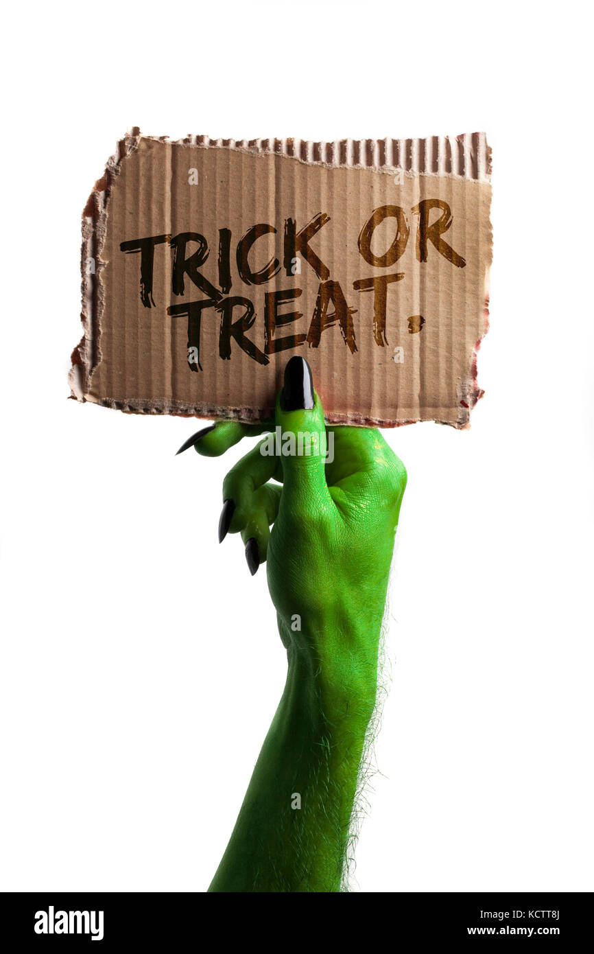 Dolcetto o scherzetto. verde streghe o zombie monster mano che tiene una scheda di halloween segno Foto Stock