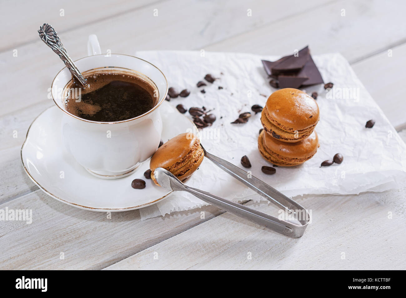 Pezzi di cioccolato con una tazza di caffè presentata su un tovagliolo bianco decorato con sciolto i chicchi di caffè e caffè aromatizzati macarons Foto Stock