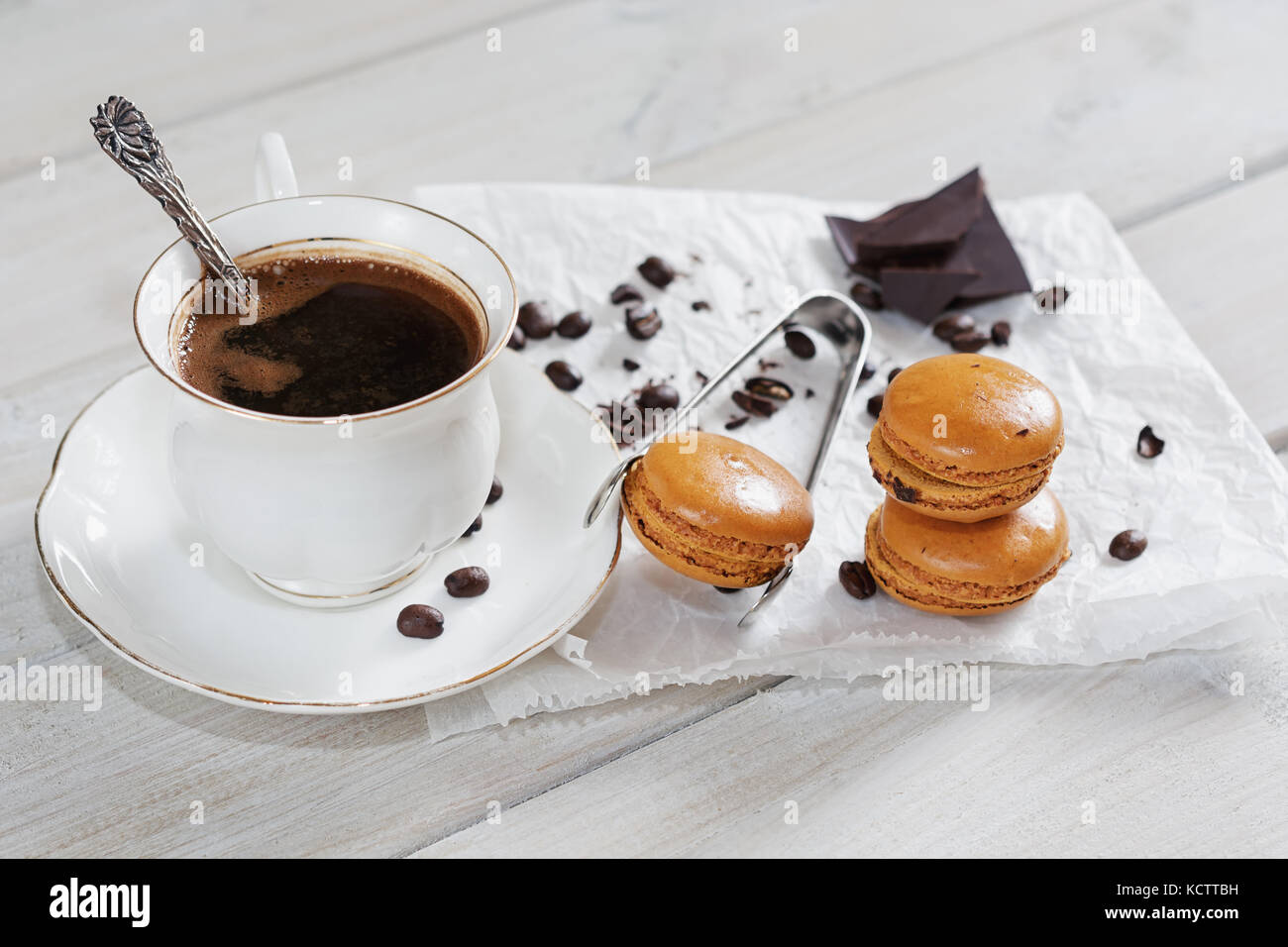 Pezzi di cioccolato con una tazza di caffè presentata su un tovagliolo bianco decorato con sciolto i chicchi di caffè e caffè aromatizzati macarons Foto Stock