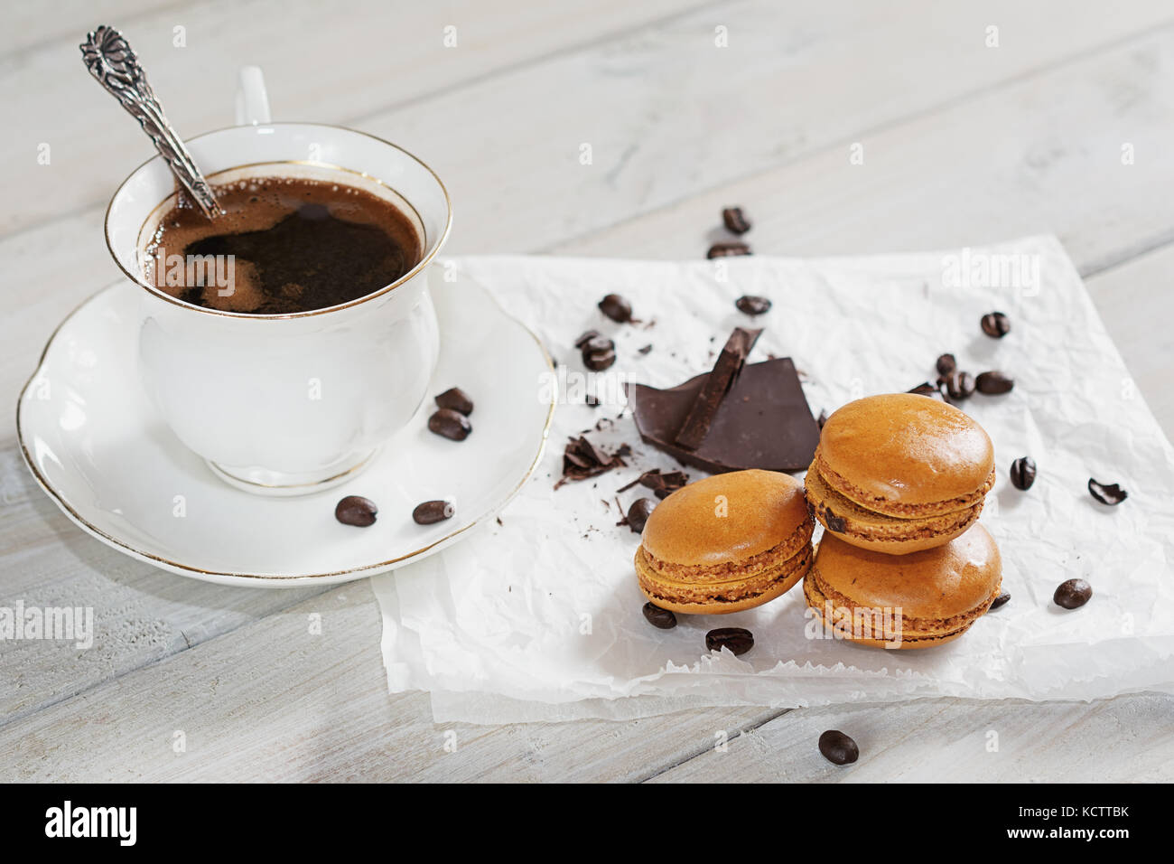 Pezzi di cioccolato con una tazza di caffè presentata su un tovagliolo bianco decorato con sciolto i chicchi di caffè e caffè aromatizzati macarons Foto Stock