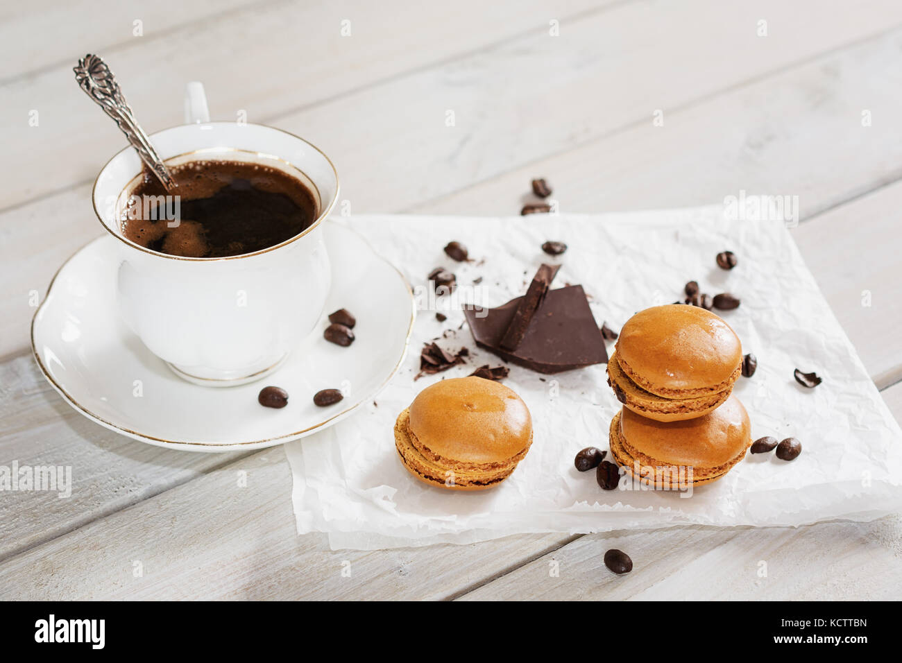 Pezzi di cioccolato con una tazza di caffè presentata su un tovagliolo bianco decorato con sciolto i chicchi di caffè e caffè aromatizzati macarons Foto Stock