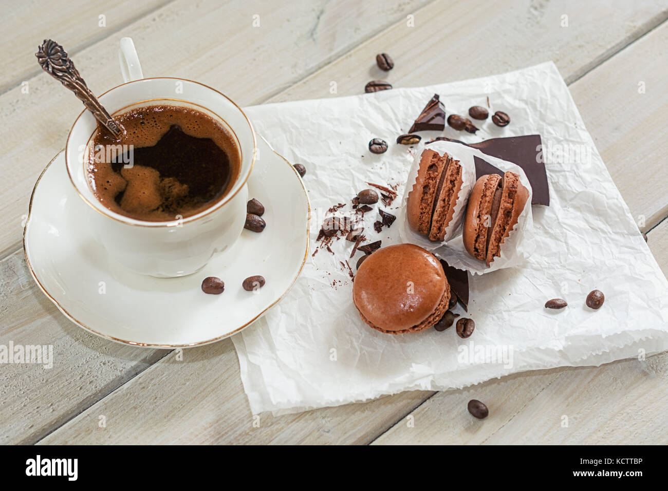 Pezzi di cioccolato con una tazza di caffè presentata su un tovagliolo bianco decorato con sciolto i chicchi di caffè e caffè aromatizzati macarons Foto Stock