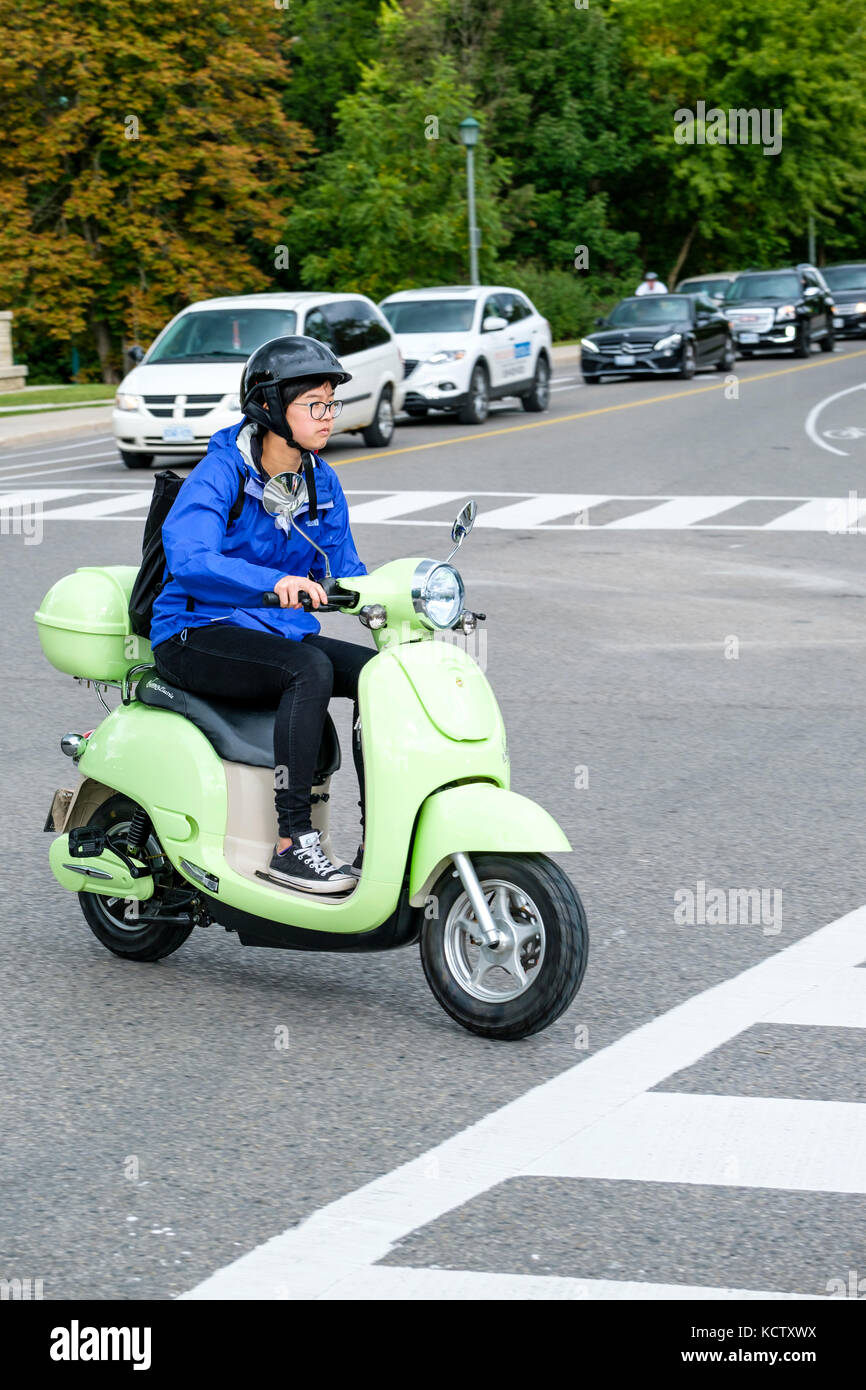 Giovane studentessa a cavallo di un canadese-fatto motorino verde XPe scooter elettrico (e-scooter), Università di Western Ontario, London, Ontario, Canada. Foto Stock