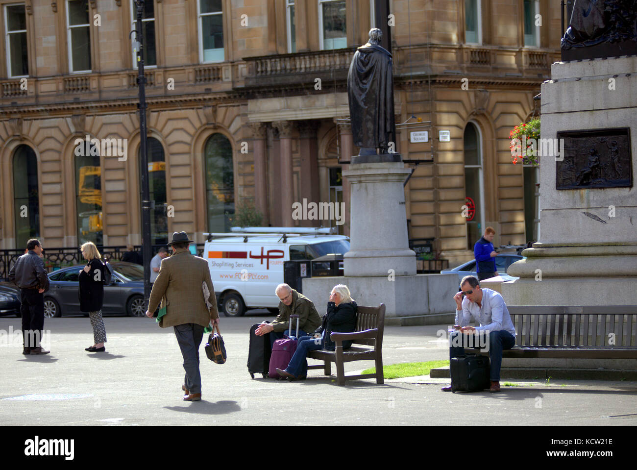 Seduto su una panchina guardando la vita che passa dai turisti George Square Glasgow Foto Stock