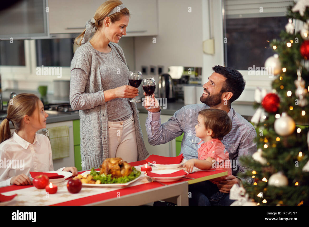 La moglie al marito la tostatura con un bicchiere di vino rosso durante il gala cena di natale Foto Stock