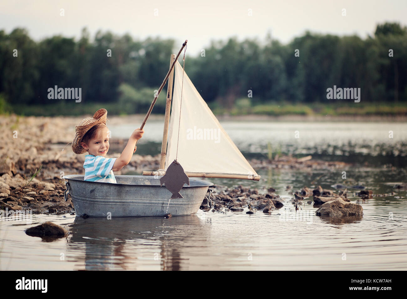 Poco carino sailor sul fiume in barca da pesca, vela Foto Stock