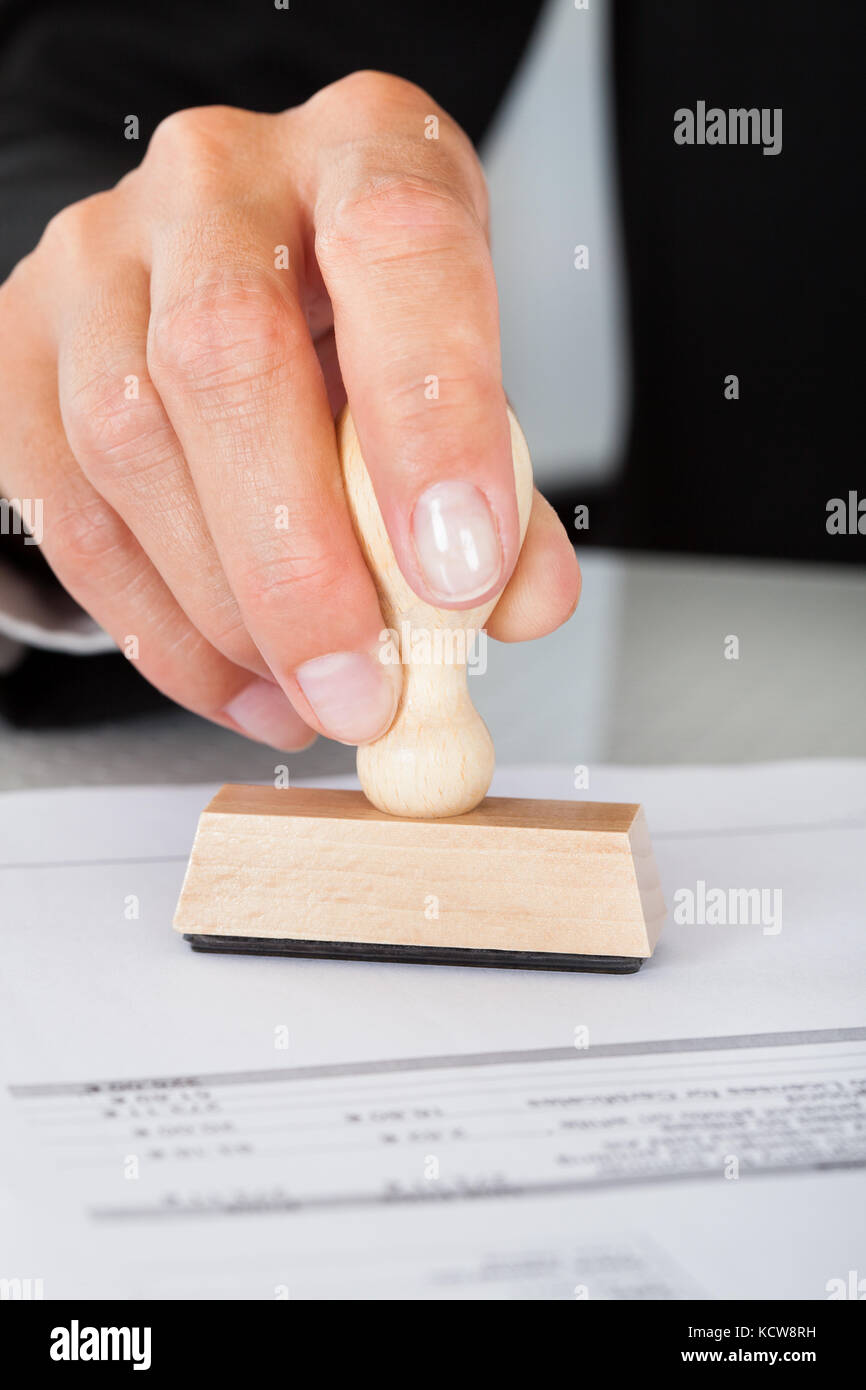Close-up di business man mano, premendo il timbro di gomma sul documento Foto Stock