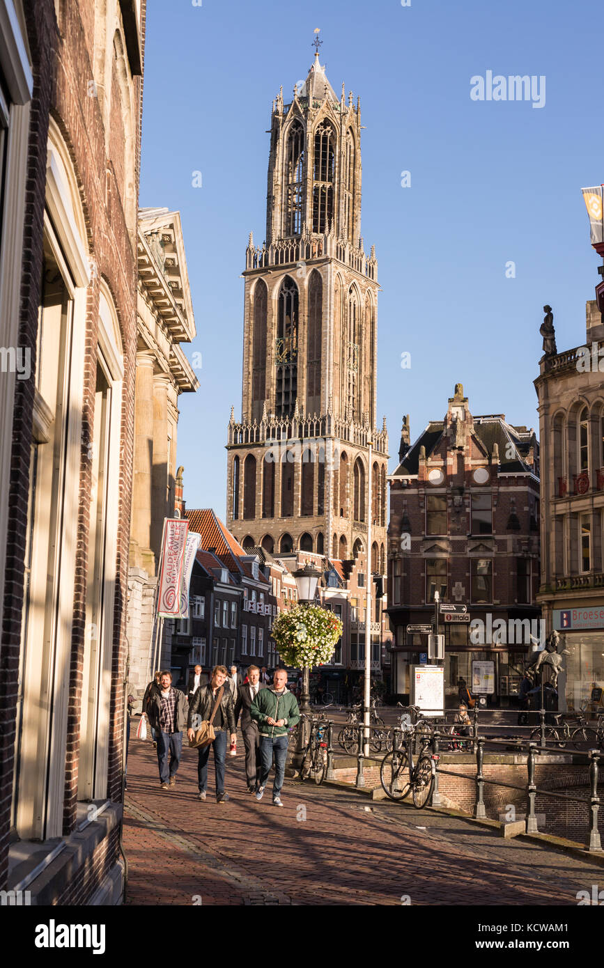 La gente che camminava per strada nel centro di Utrecht con la vista del Dom Tower di Saint Martins cattedrale in background Foto Stock