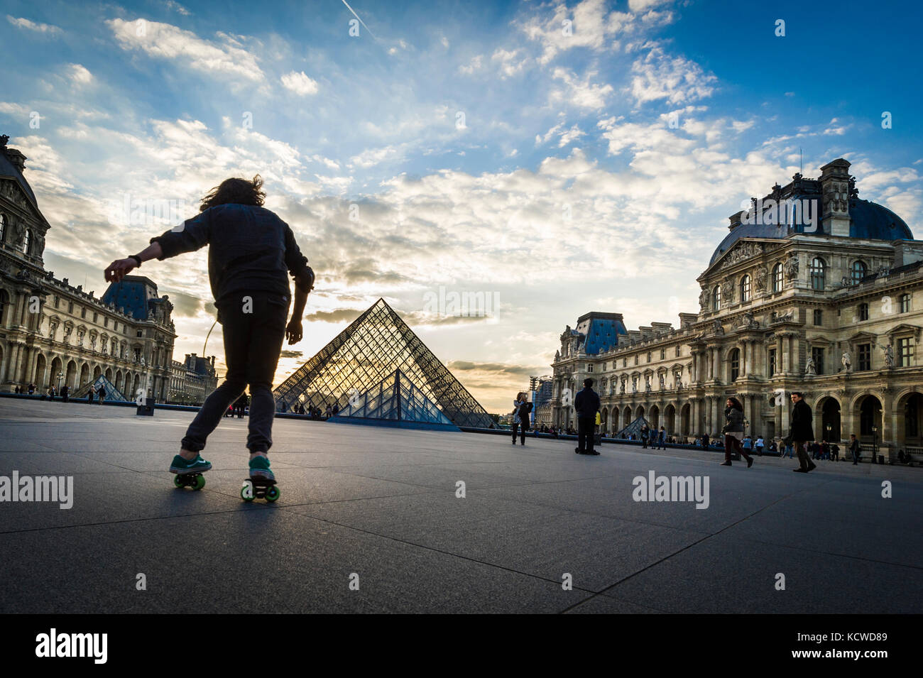 Pattinaggio pratica presso la Piramide del Louvre al tramonto Foto Stock