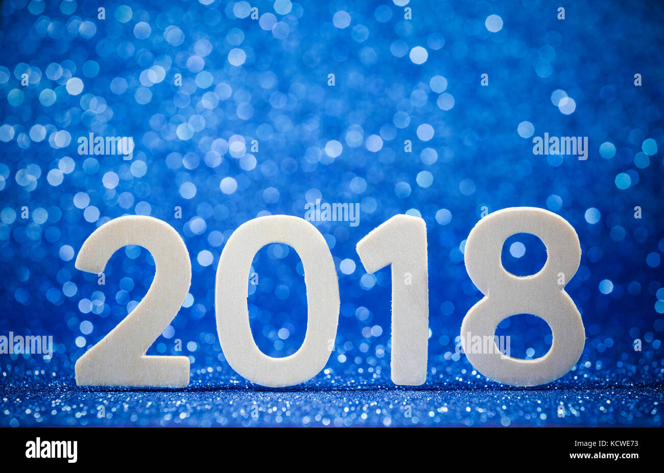 Nuovo anno 2018 bianco numero di legno su carta blu glitter con luci. mock up banner spazio per il display o il montaggio di prodotto, presentazione del business. Foto Stock