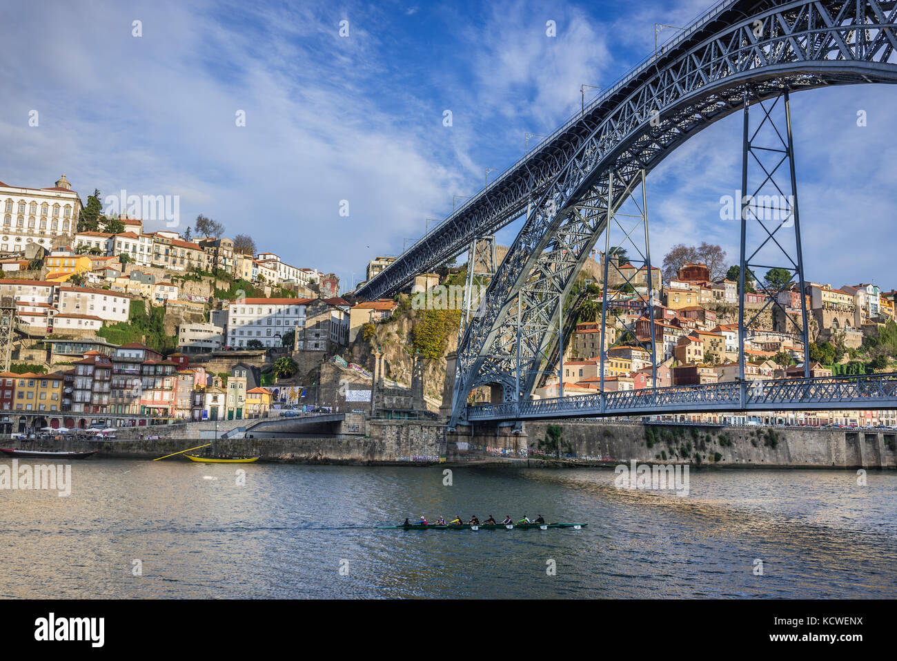 Vogatori in un coxed otto, una barca a remi spazzata sul fiume Douro visto dalla città di Gaia, Portogallo. Porto città sullo sfondo, vista con il ponte Dom Luis I. Foto Stock