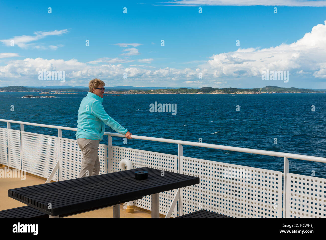 Donna adulta in blu maglione sul traghetto dalla Norvegia alla Svezia con il Coast della Svezia come sfondo Foto Stock