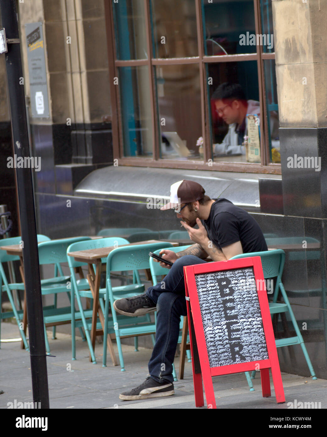 Segno di birra glasgow cafe bar esterno tabelle utilizzando lo smartphone Sigaretta fumare Foto Stock