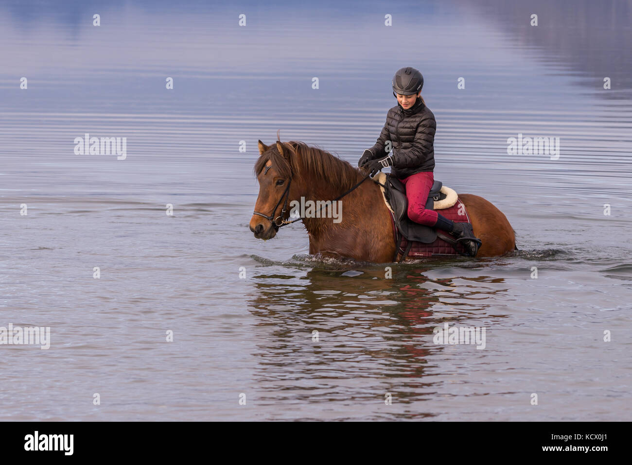 Young Teen ragazza di equitazione in oceano in una spiaggia Foto Stock