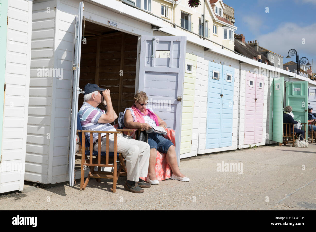 Giovane seduto fuori beach hut lungo la Marine Parade, Lyme Regis, Dorset, England, Regno Unito, Europa Foto Stock
