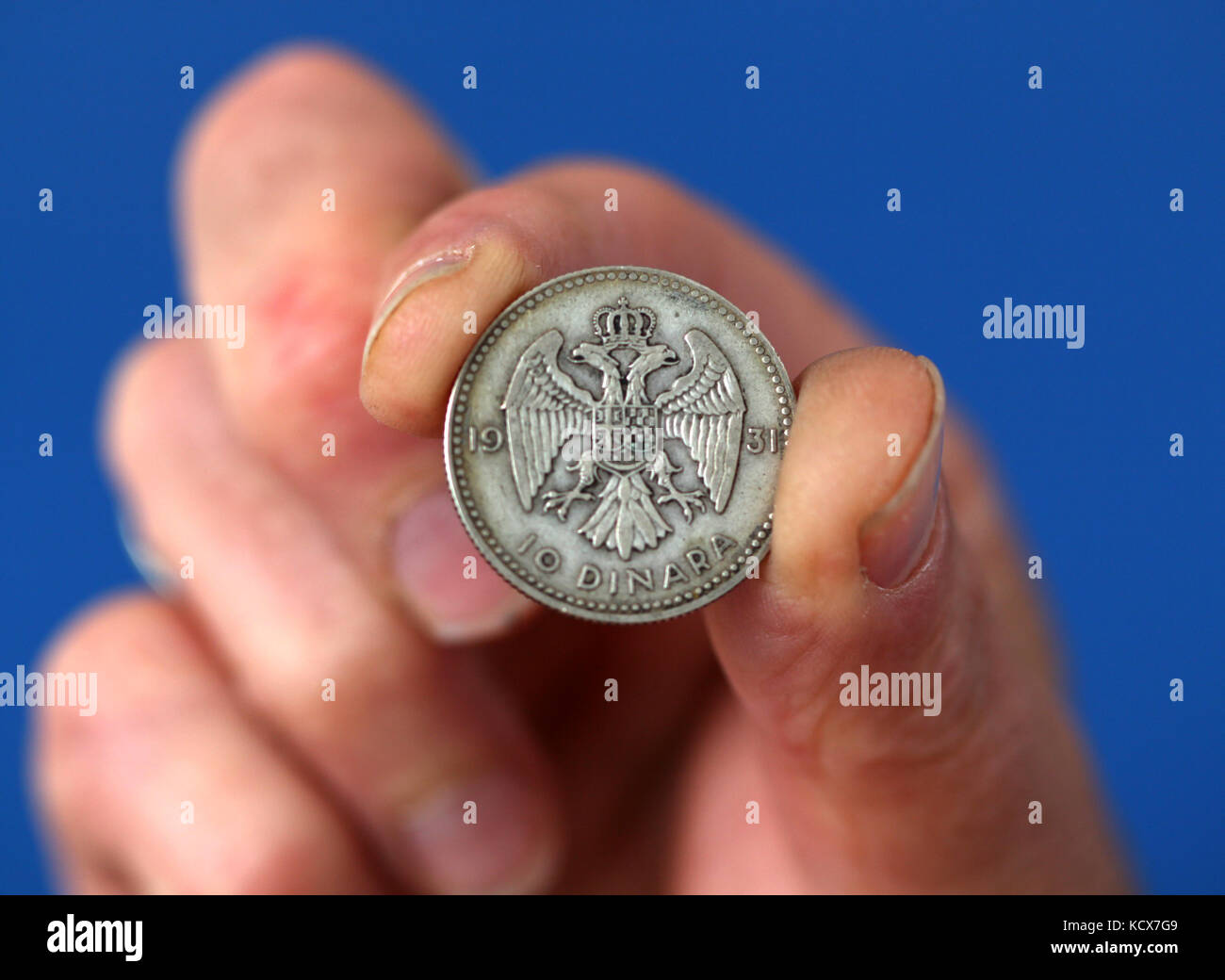 Immagine di una dita tenere vecchia moneta dalla Iugoslavia unito Foto Stock