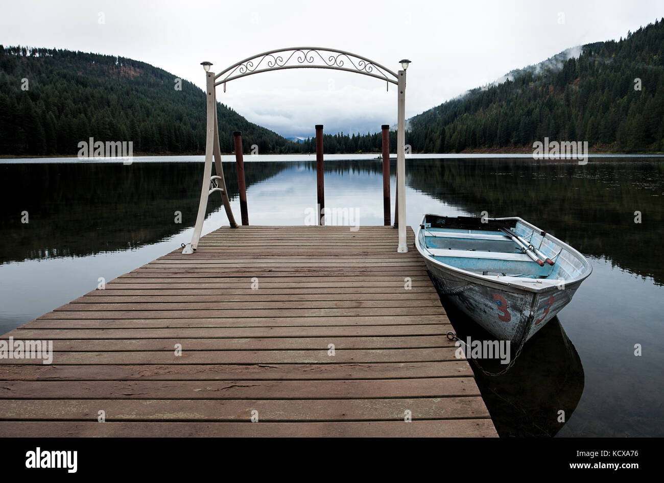 Un piccolo canotto è ancorata a un dock sul tranquillo lago specchio vicino sagle, Idaho. Foto Stock