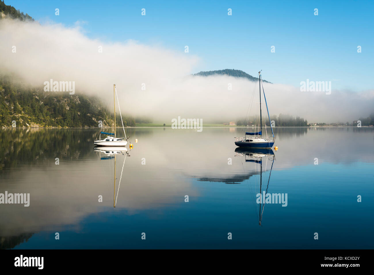 Mist, montagne, barche a vela e yacht al sole del mattino si riflette nella superficie calma del lago Achensee in autunno, Tirolo, Austria Foto Stock