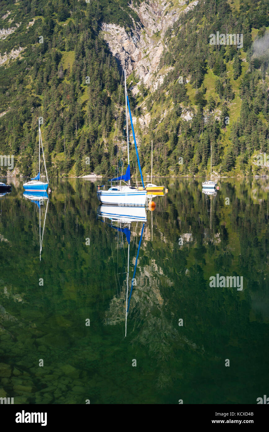 Mist, montagne, barche a vela e yacht al sole del mattino si riflette nella superficie calma del lago Achensee in autunno, Tirolo, Austria Foto Stock