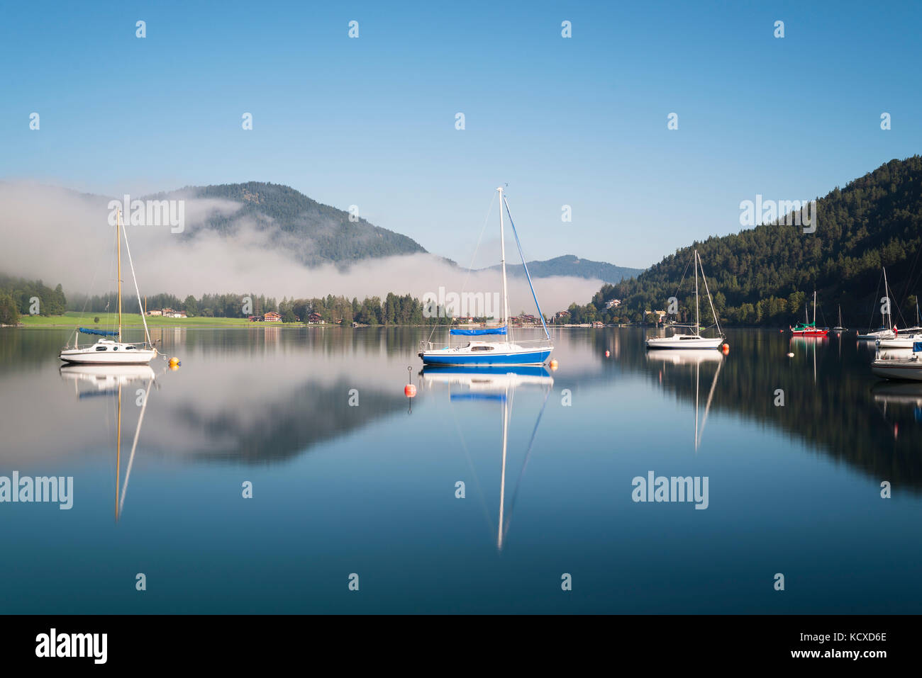 Mist, montagne, barche a vela e yacht al sole del mattino si riflette nella superficie calma del lago Achensee in autunno, Tirolo, Austria Foto Stock