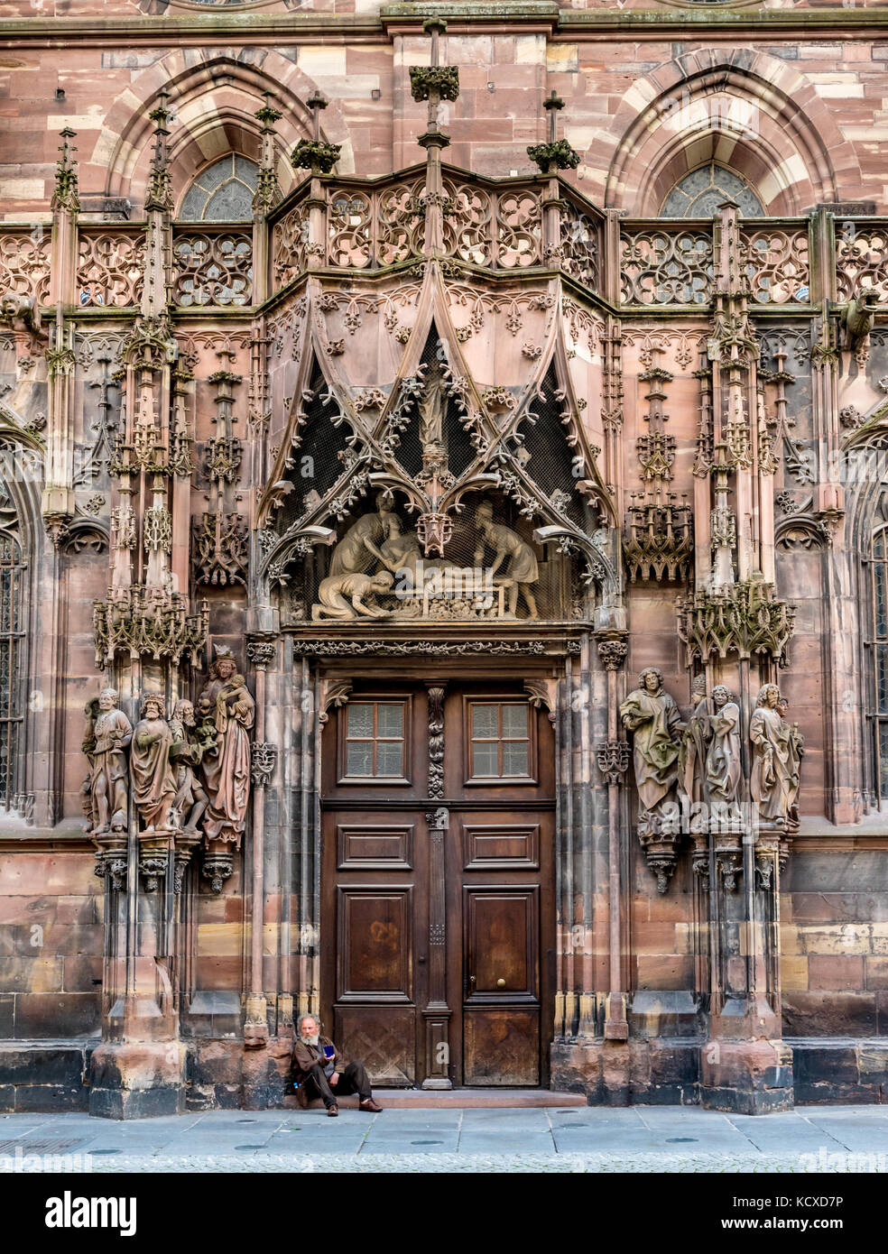 Porta nord della Cattedrale di Strasburgo con mendicante seduta sui gradini Foto Stock