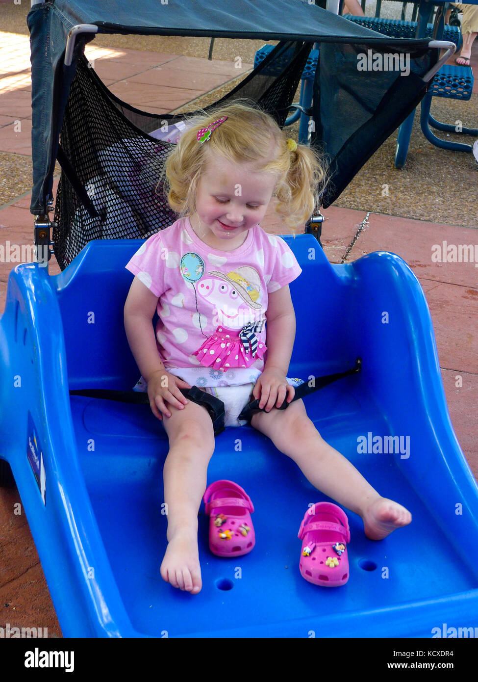 Bambino sorridente, seduti nel parco a tema doppio passeggino buggy  indossando peppa pig t-shirt Disney, Florida crocs bambina bambini scalzi  bimbi felici Foto stock - Alamy