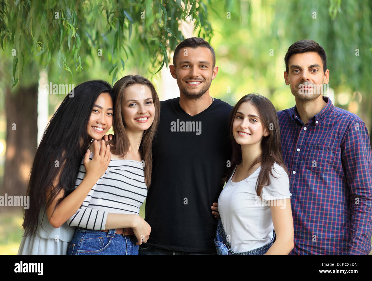 Cinque donne e uomini amici sulla foresta verde dello sfondo. mezzo corpo ritratto di multi razziale amici nel parco su estate giornata soleggiata. bella felice carefre Foto Stock