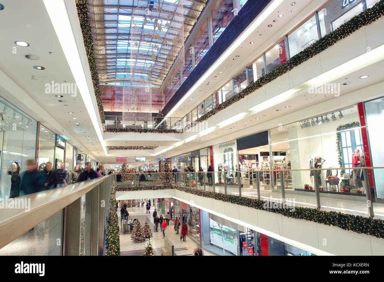 Gli acquirenti di fare gli acquisti di natale in grande centro shopping decorata con ornamenti natale e le luci Foto Stock