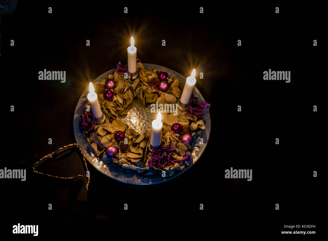 La corona dell'Avvento con quattro candele brucianti su un barile d'argento, in piedi su un tavolo nero con i vetri. Frederikssund, Danimarca, 30 dicembre 2016, Foto Stock