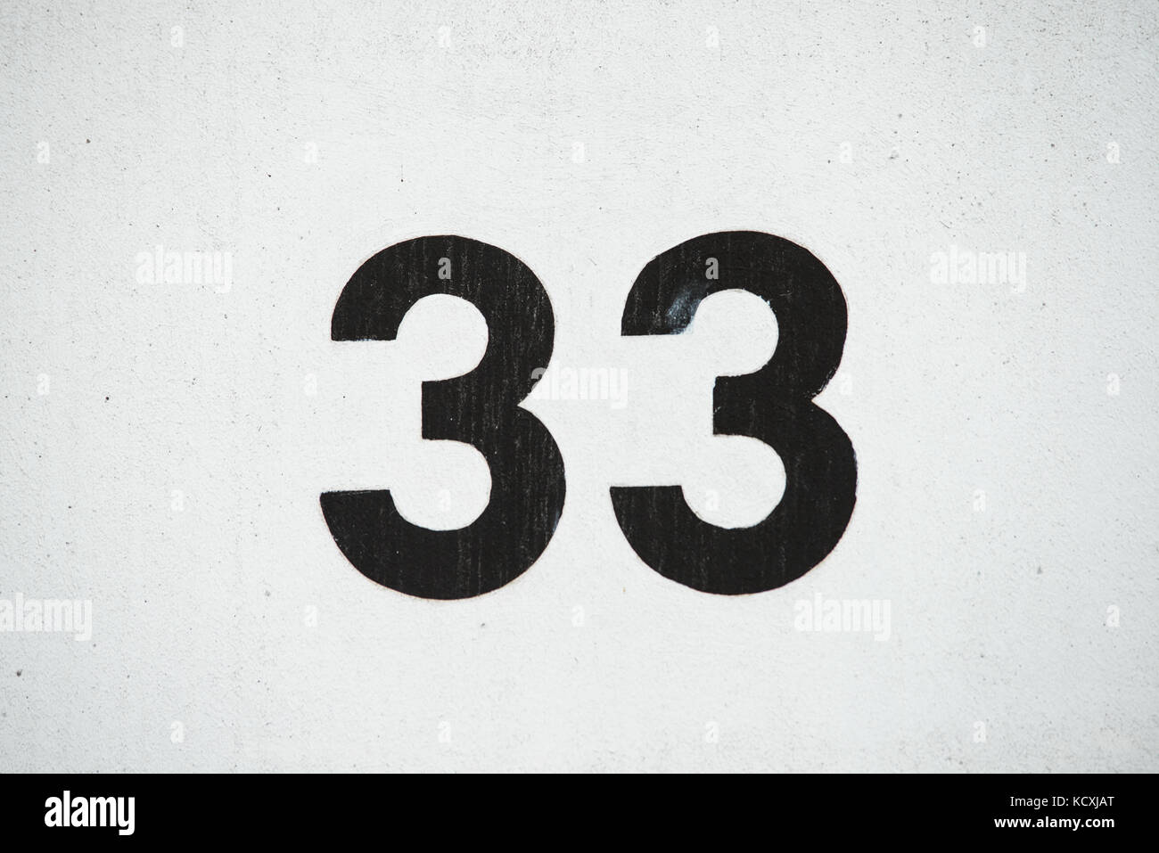 Numero 33 trentatre dipinta su un muro bianco Foto Stock