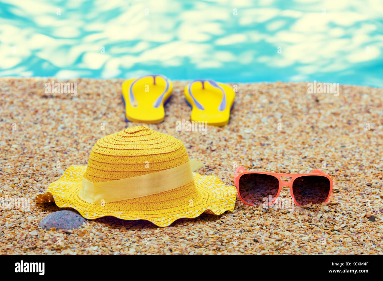 Scena di spiaggia. Sun cappello di paglia, flip flop sandali e occhiali da sole giacente sul mare coquina conchiglie sulla spiaggia Foto Stock